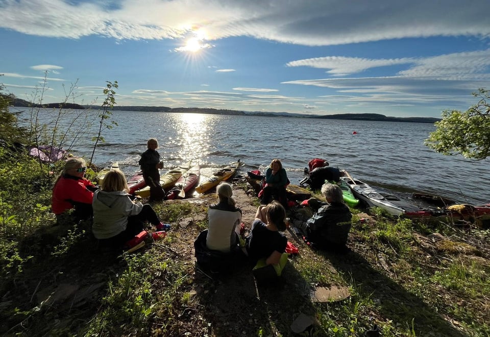 Bildet visere padlere i solnedgang. De er på land og har en pause.
