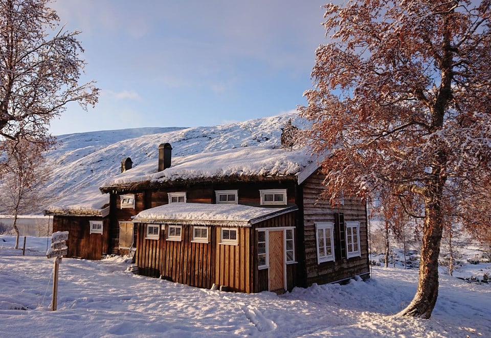 Tømmerhytte i snø.