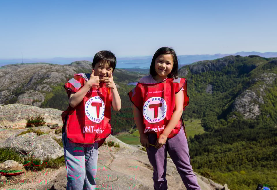 To barn med røde T-vester smiler til kamera.