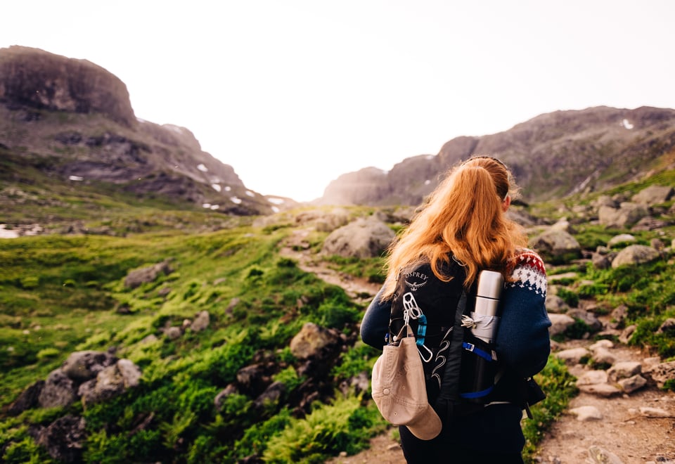 Foto. Turgåer med sekk. Fjell og grønt gress.