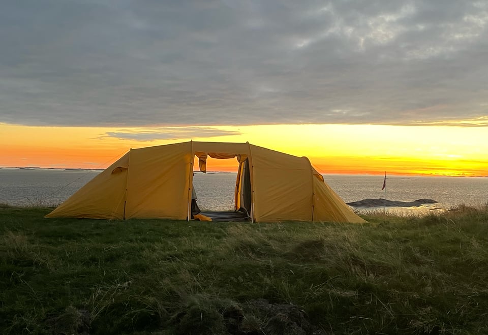 Bilde av et gult telt i solnedgangen.