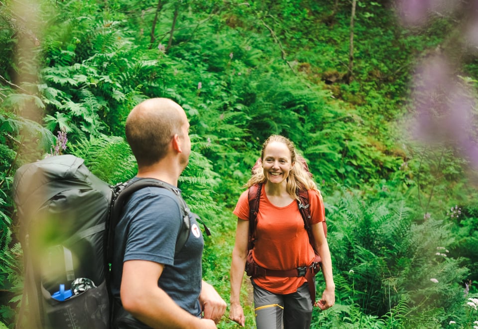 Mann og kvinne går på frodig sti smilende