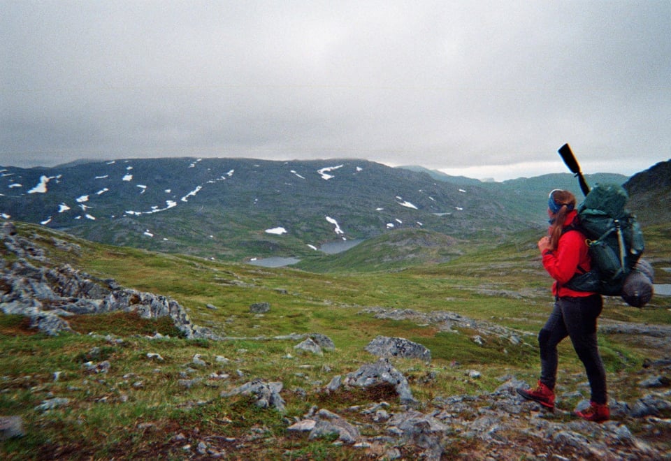 Jente med rød jakke og tursekk ser utover Sørøya