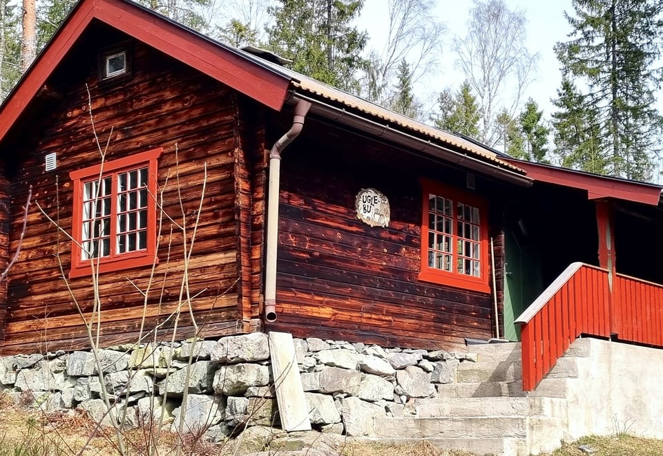 Gammel tømmerkoie med røde karmer og steinlagt grunnmur
