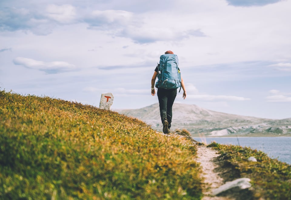 Person som går på tursti på fjellet, med utsikt