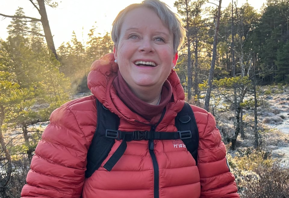 Smilende kvinne på tur i skogen. Foto.