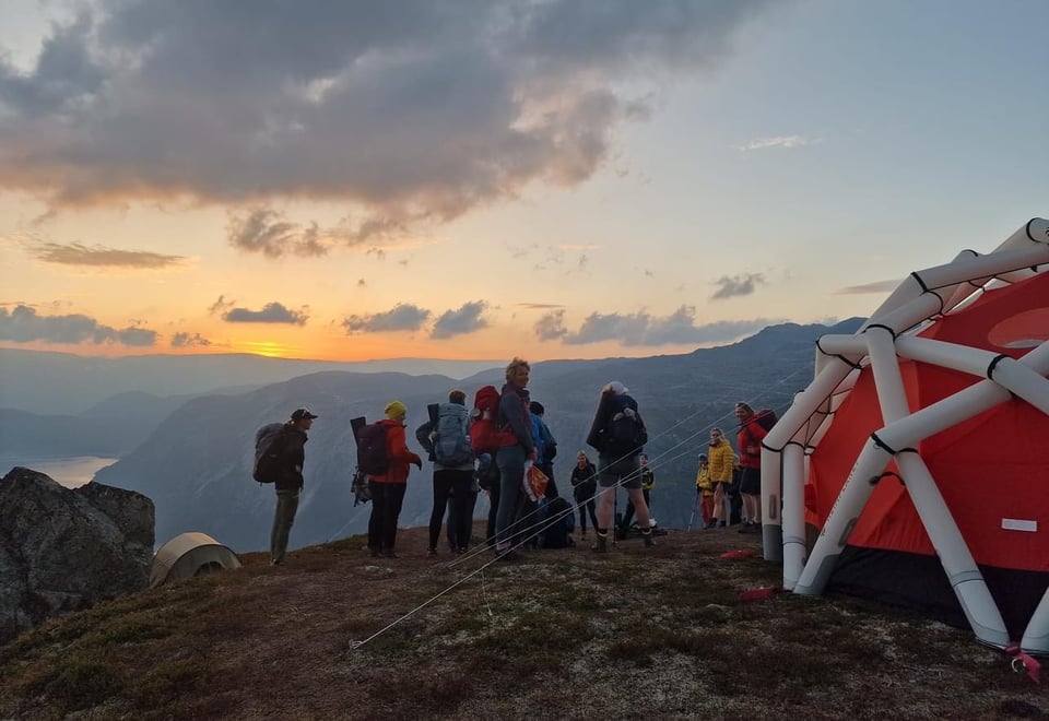 En gruppe på tur om kvelden foran et telt.