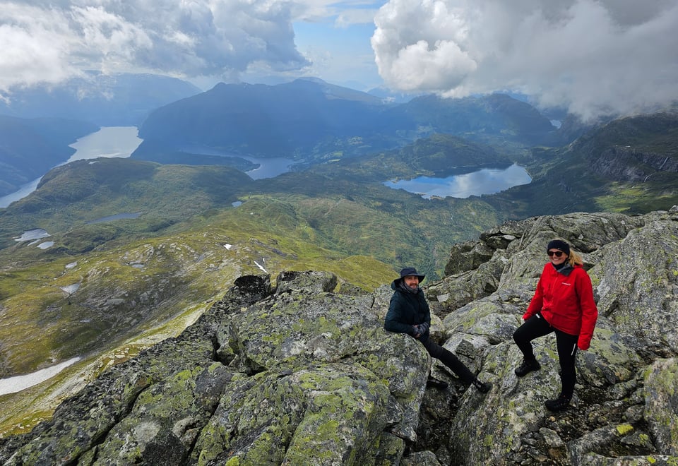Kvite skyer, grøne fjellsider med fjord og vatn