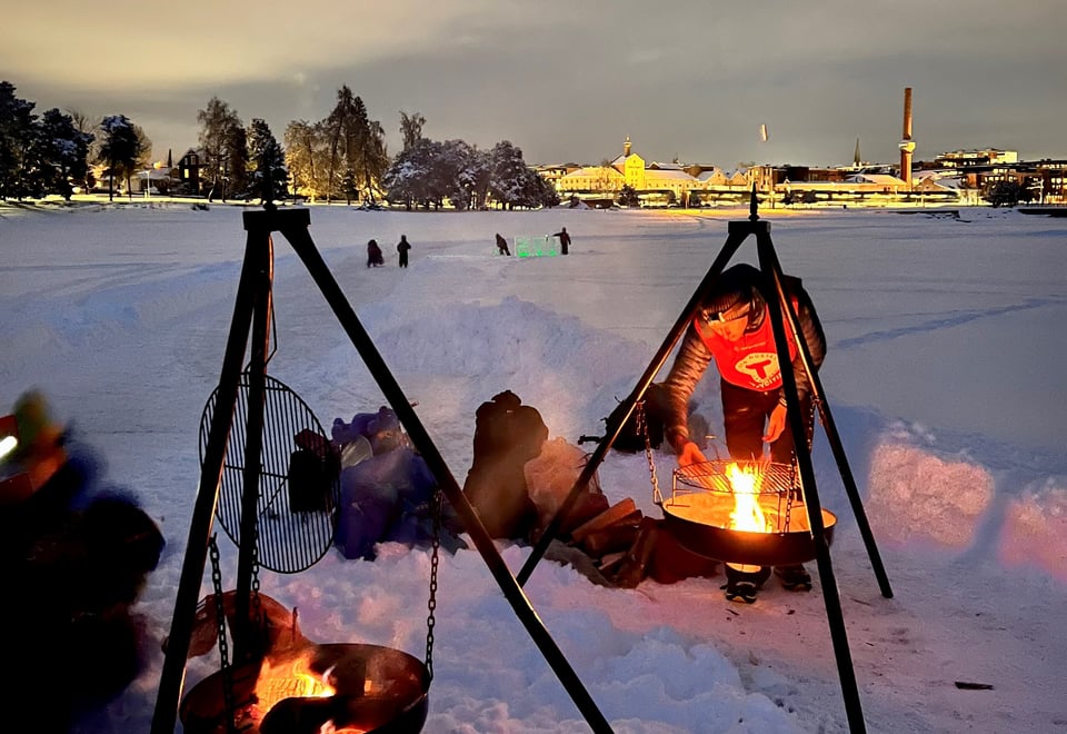 Mann fyrer opp i bålpanne på vinteren.