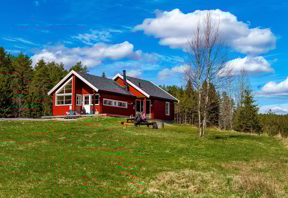 Mennesker som sitter foran den røde Østtorphytta. Foto.