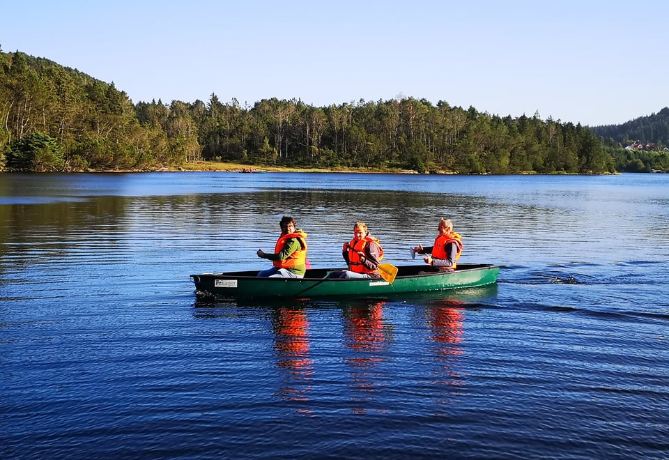 Tre personer sitter i en kano og padler et vann. Foto.