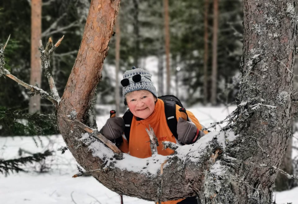 Dame lener seg mot furu og smiler