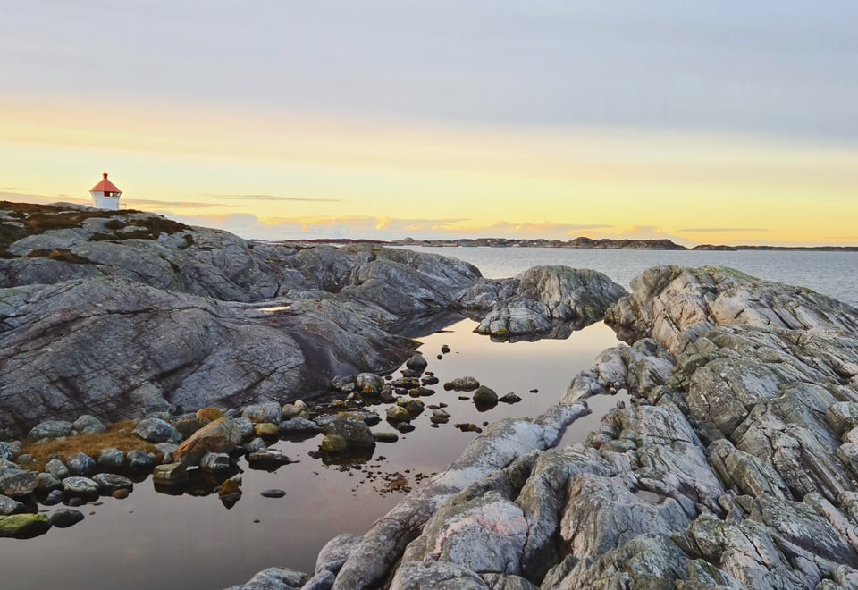 Svaberg og fyrlykt i solnedgang. Et lite vann. Foto 