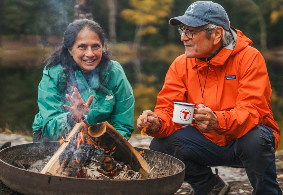 To personer som sitter rundt en bålpanne