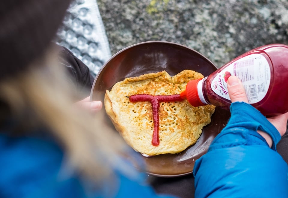 Rød T tegnet med syltetøy på pannekake, stekt ute på primus.