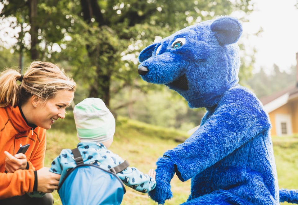 Mor og barn hilser på Turbo, maskoten til Barnas Turlag