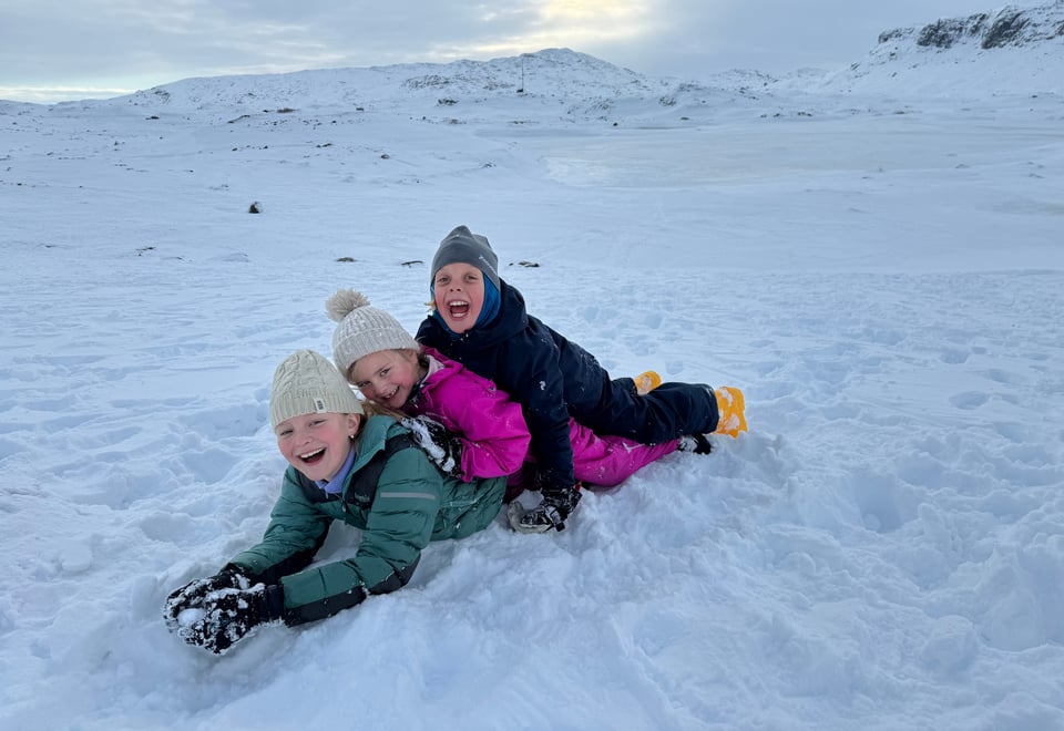 Tre barn leker i snøen