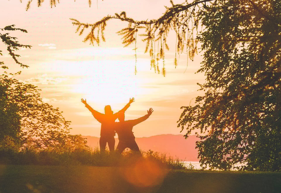 Gode venner poserer i skogen med solnedgangen i ryggen. 