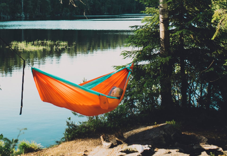 Dame som ligger i en oransje hengekøye