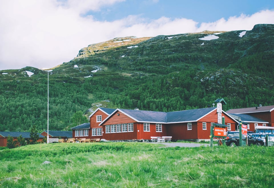 Den røde Aurlandsalen turisthytte står i stor kontrast med de frodige grønnfargene som omkranser bygget.
