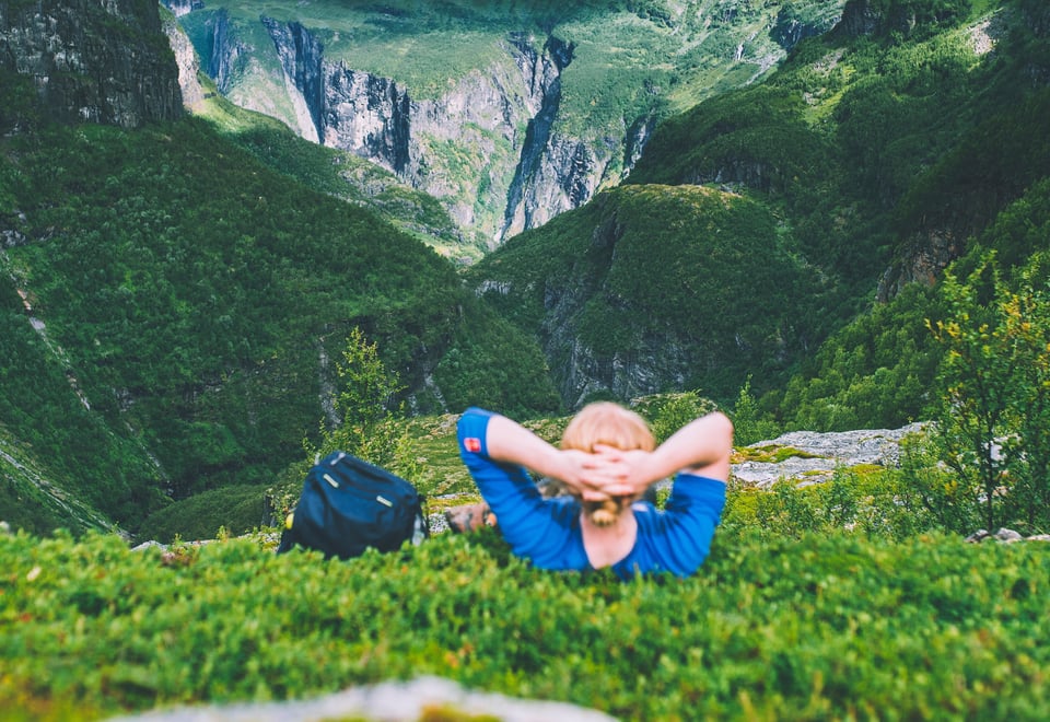 Mann ligger i lyngen og ser utover dal.