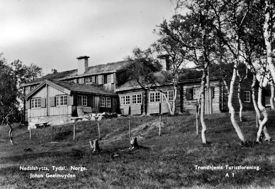 Et postkort fra 1950, som med et svart-hvitt bilde av en turisthytte, med noen trær i forgrunnen til høyre. 