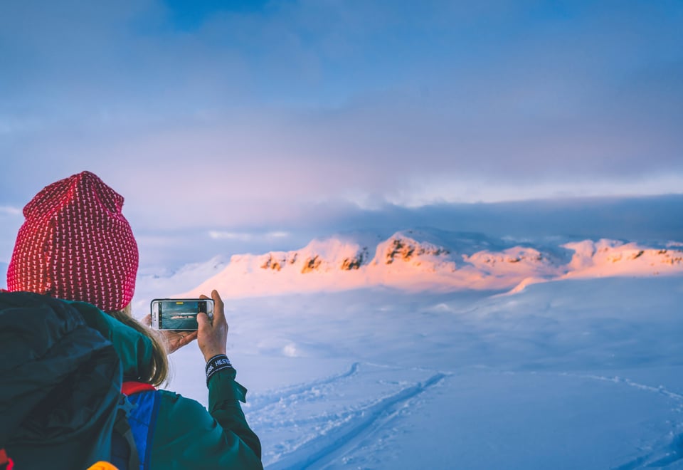 Person som tar bilde av vinterlandskap med telefon.