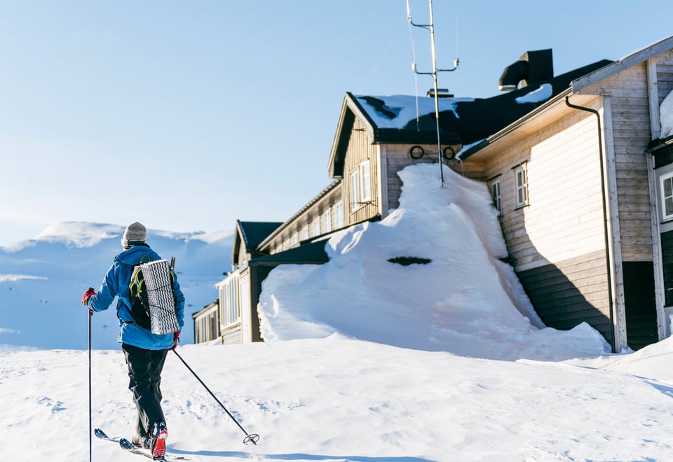 Cross country skier in front of Finsehytta on a sunny day.