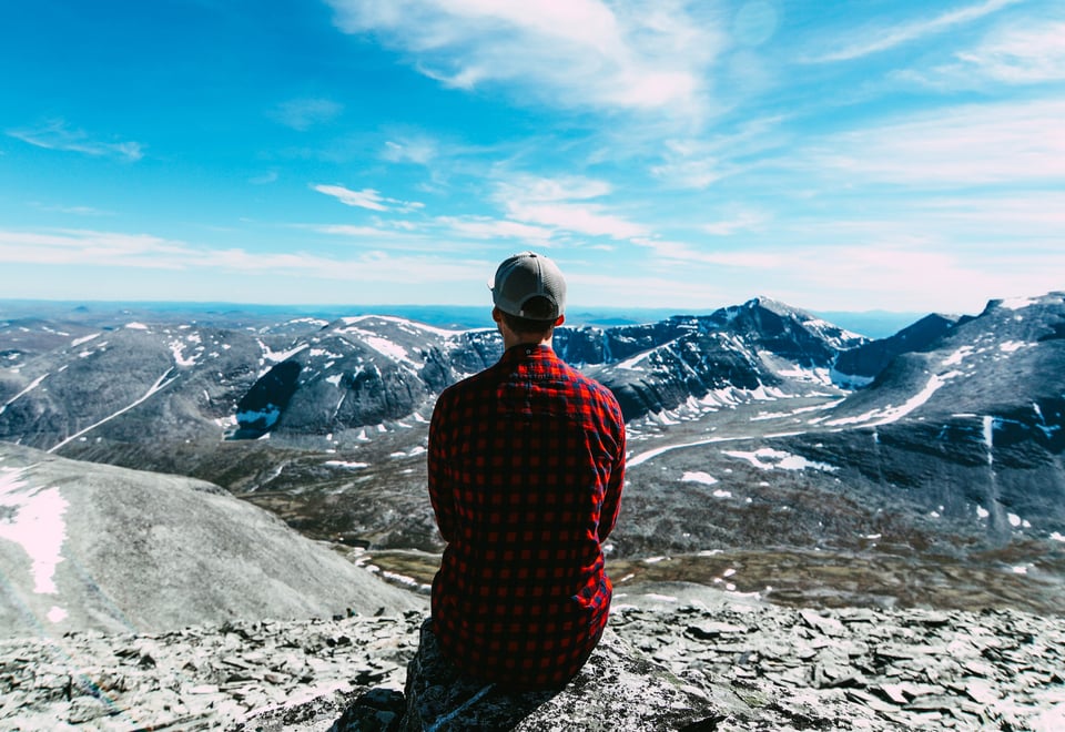 Person i rød skjorte som ser utover et fjellområde