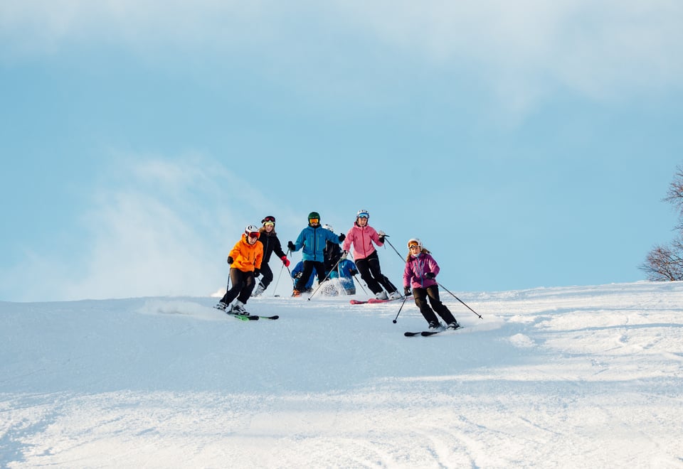 Fire skiløpere som svinger i alpinbakke.