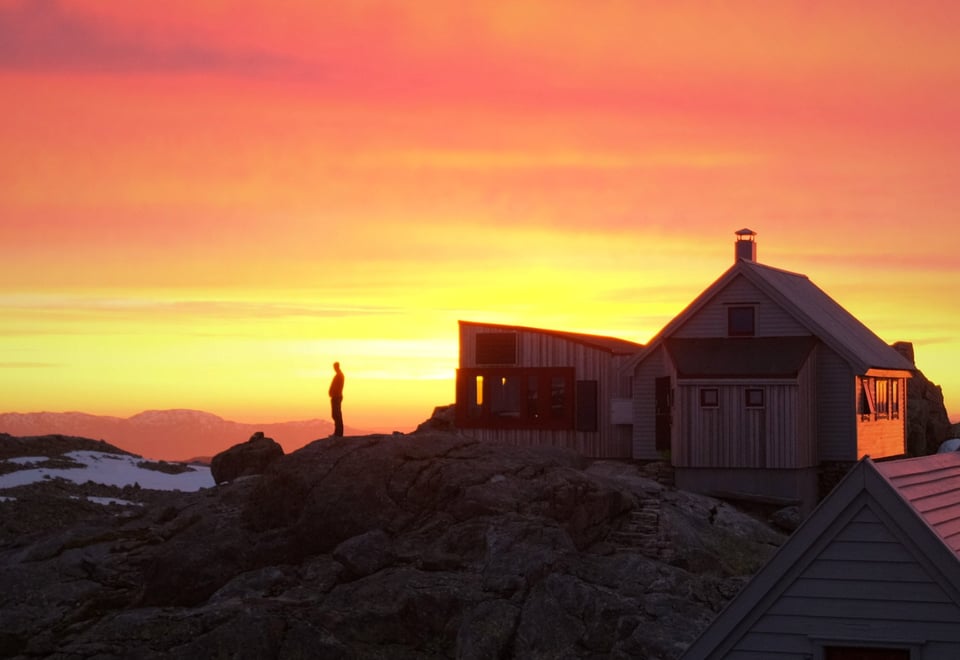 Person i siluett på en fjellknaus ved Fonnabu turisthytte.