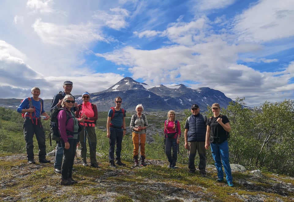 Turfølge som tar seg en pause på tur i Saltdal i nydelig sommervær. Majestetisk fjell i bakgrunnen.