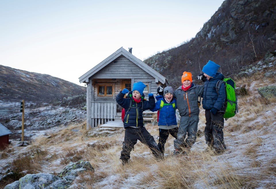 Fire barn står foran hytte i fjellet