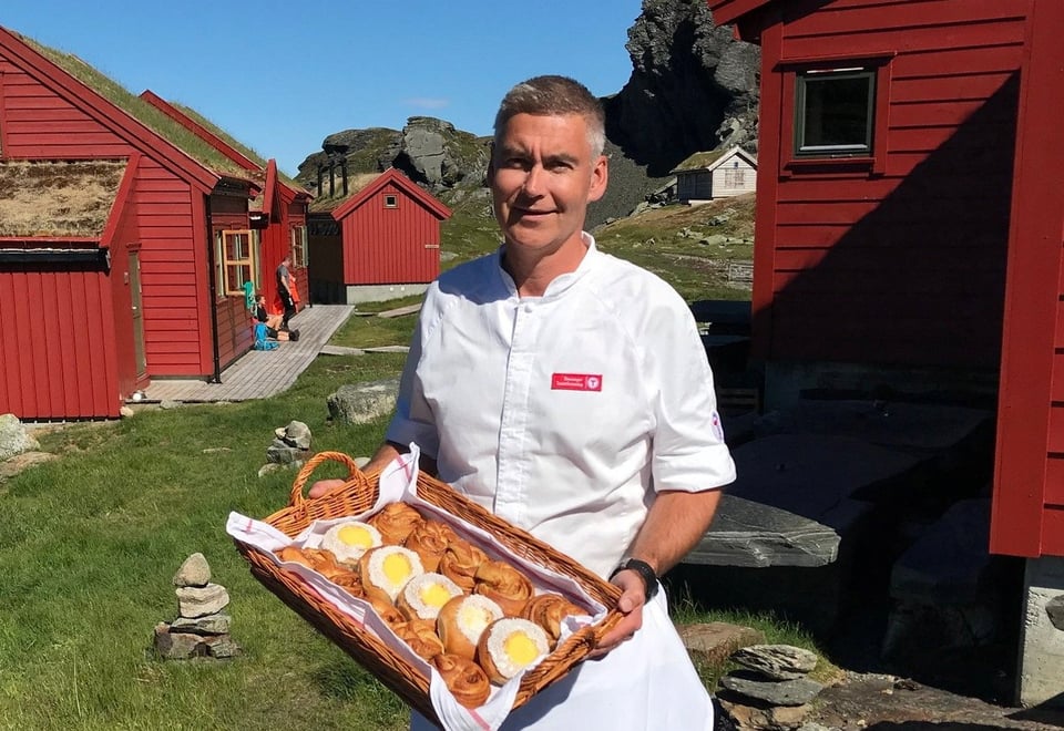 Bilde av bestyreren som holder et fat med skoleboller utenfor hytta.