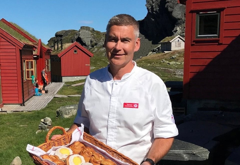 Bilde av bestyreren Halvor som holder et fat med skoleboller utenfor hytta.