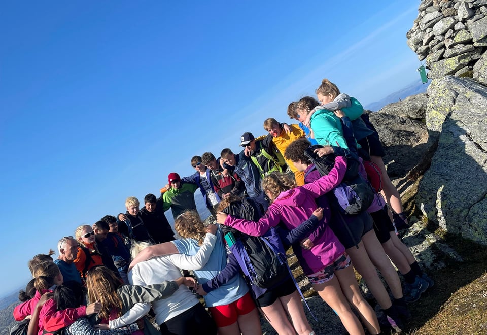 Magen ungdommer står i en sirkel og holder rundt hverandre