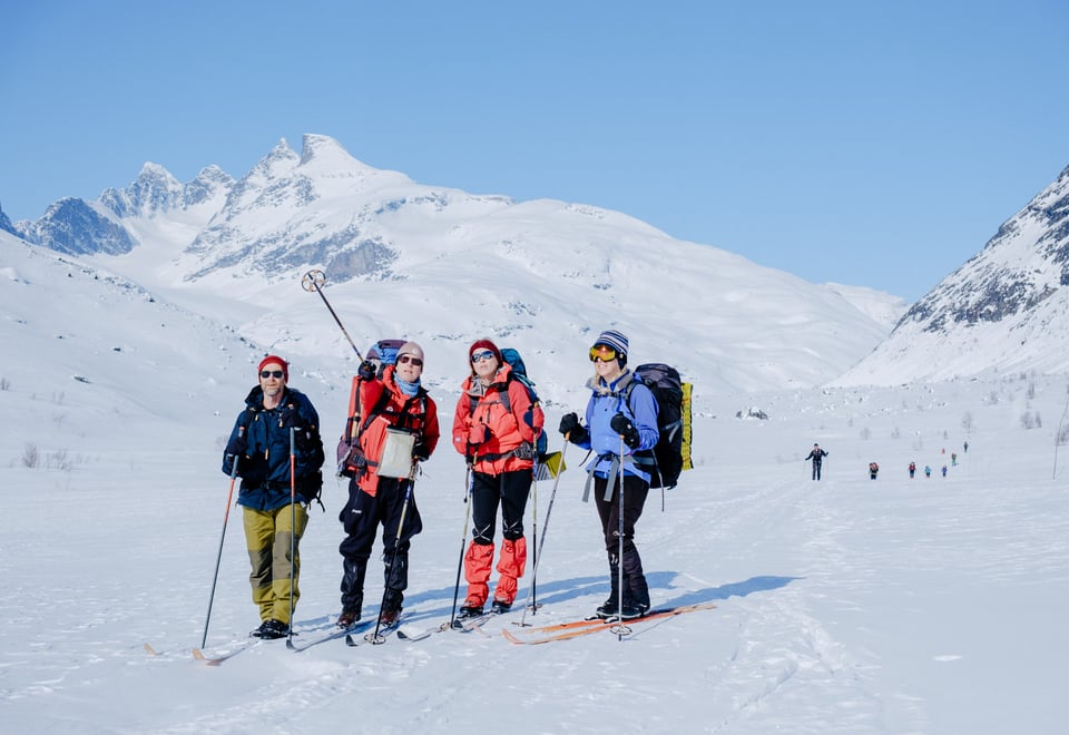 Gruppe på ski blant snøkledde fjell.