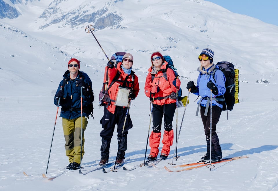Fire personer i vinterklær med ski og staver