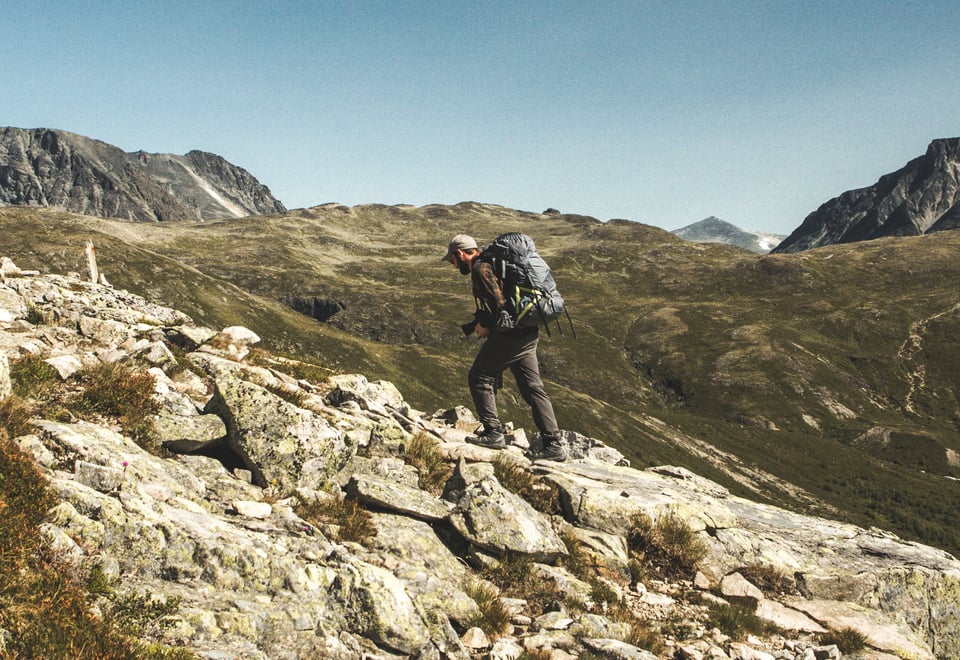 Mann med sekk som går i fjellet