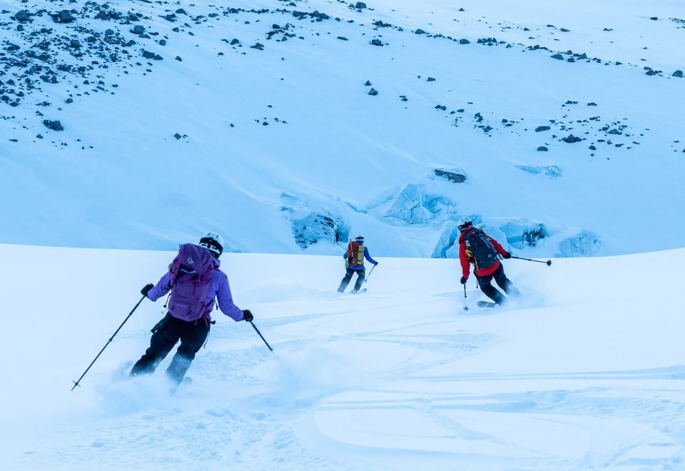 Tre personer kjører nedover på ski