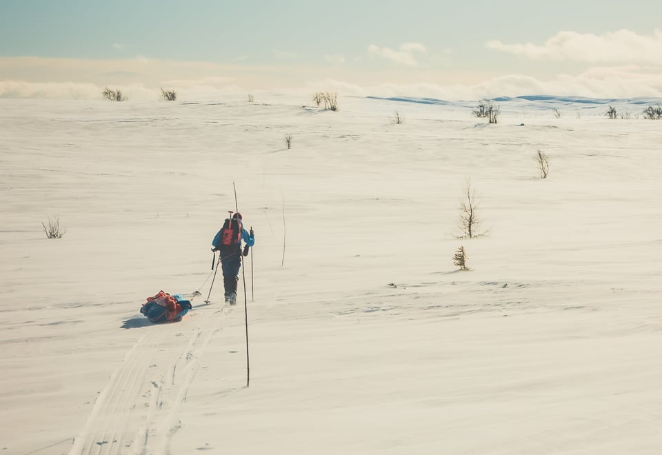 Mann med fjell og pulk som går langs en kvistet løype