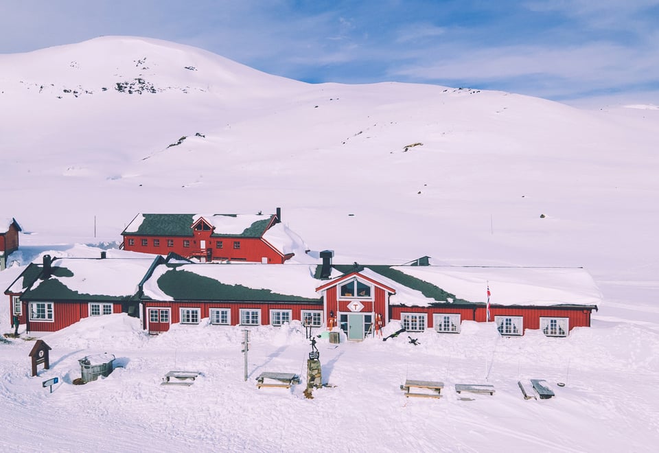 Rød hytte i vinterfjellet.