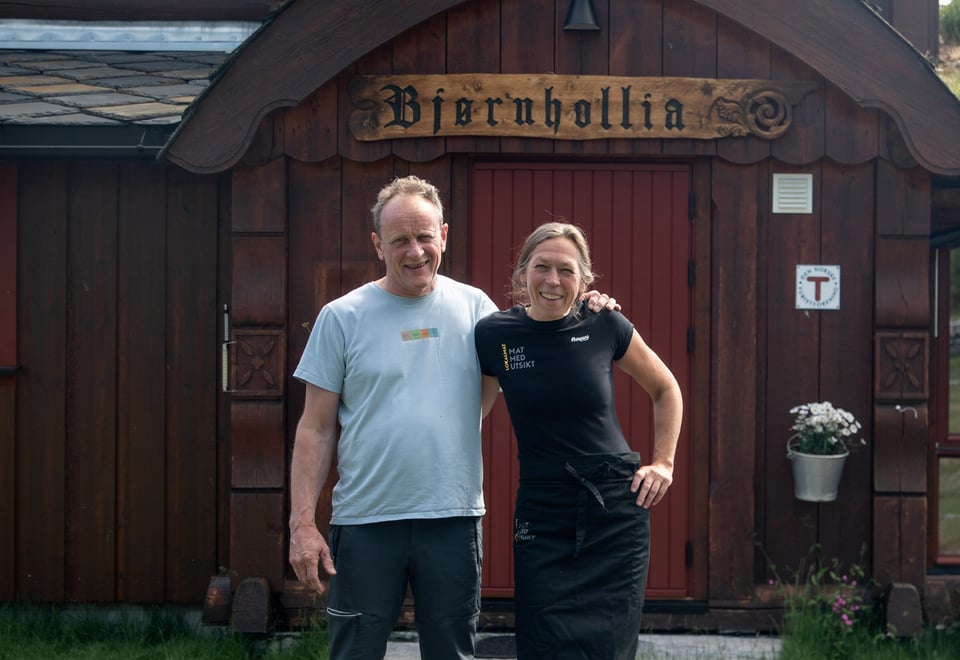 En mann og dame som holder rundt hverandre foran en hytte