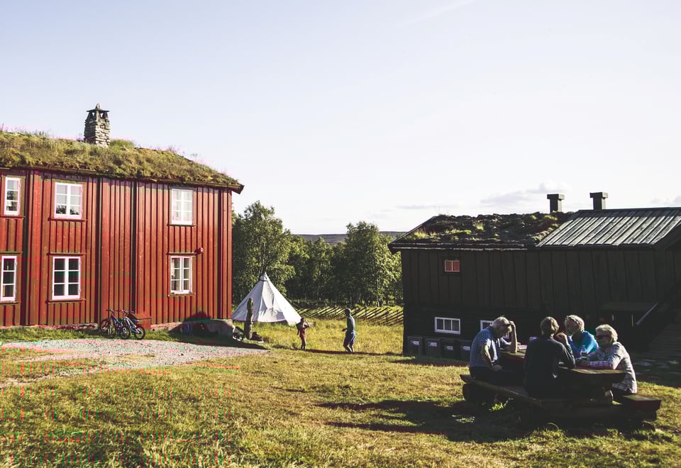 Dronebilde av hytta og gårdstunet i vinterlige forhold. 