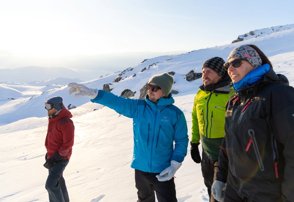 Fire personer kikker bort på noe i vinterlandskap.