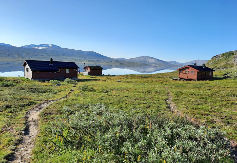 Begge hyttene ved Bjellåvasstua bader i sol en flott sommerdag.
