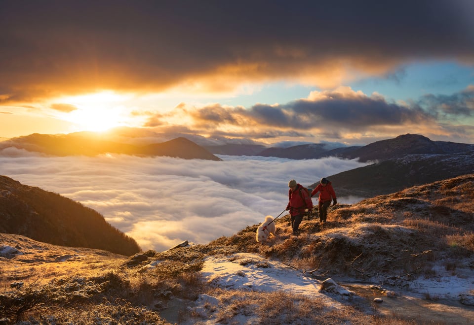 To personer på tur over skydekkede fjell.