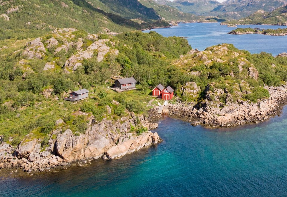hytte i vannkanten, flotte fjell i bakgrunnen