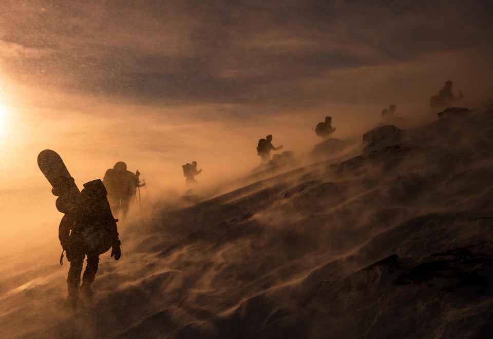 Mennesker går opp på fjell i snøen