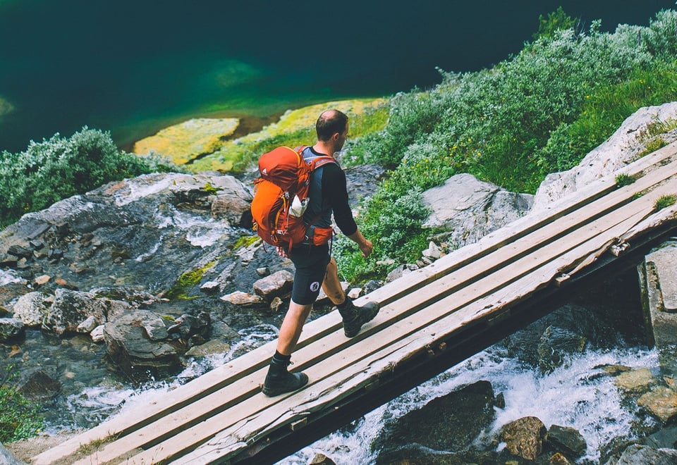 Mann går på bru i fjellandskap